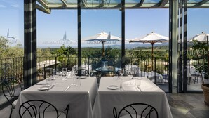 Un restaurant avec des tables dressées pour le service, de grands parasols et une vue sur le paysage.