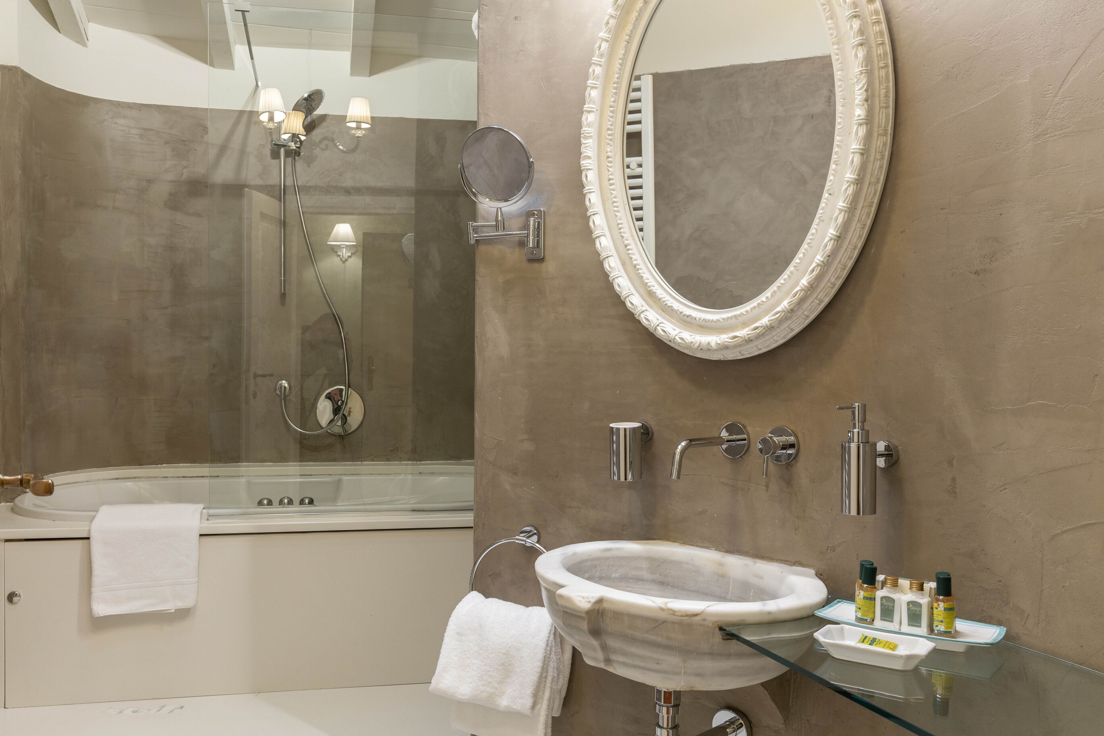 Un baño moderno con ducha de vidrio, lavamanos de mármol y un espejo grande.