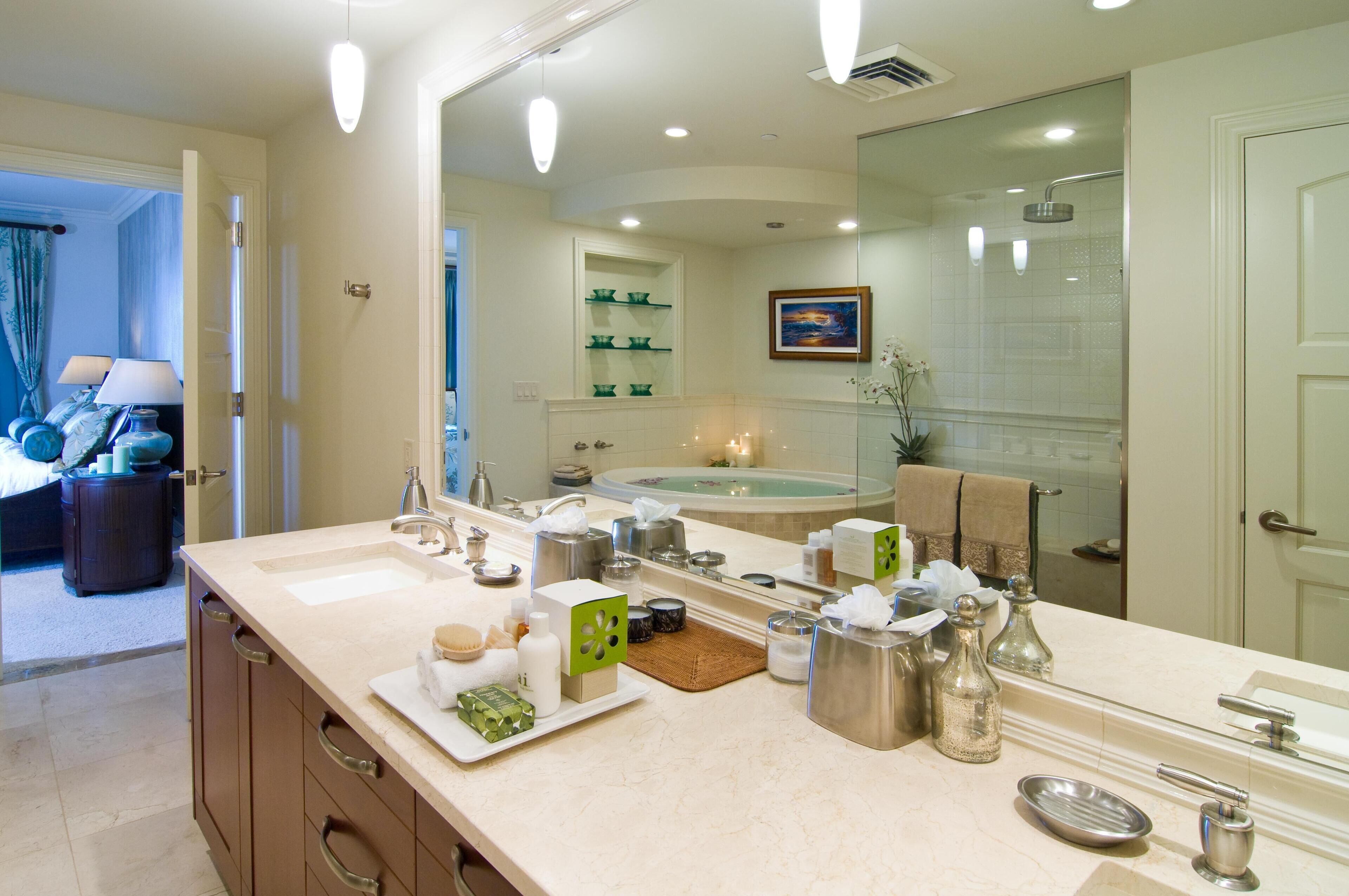 A bathroom with a large mirror, a bathtub, and a shower. There are toiletries on the counter and a towel rack.