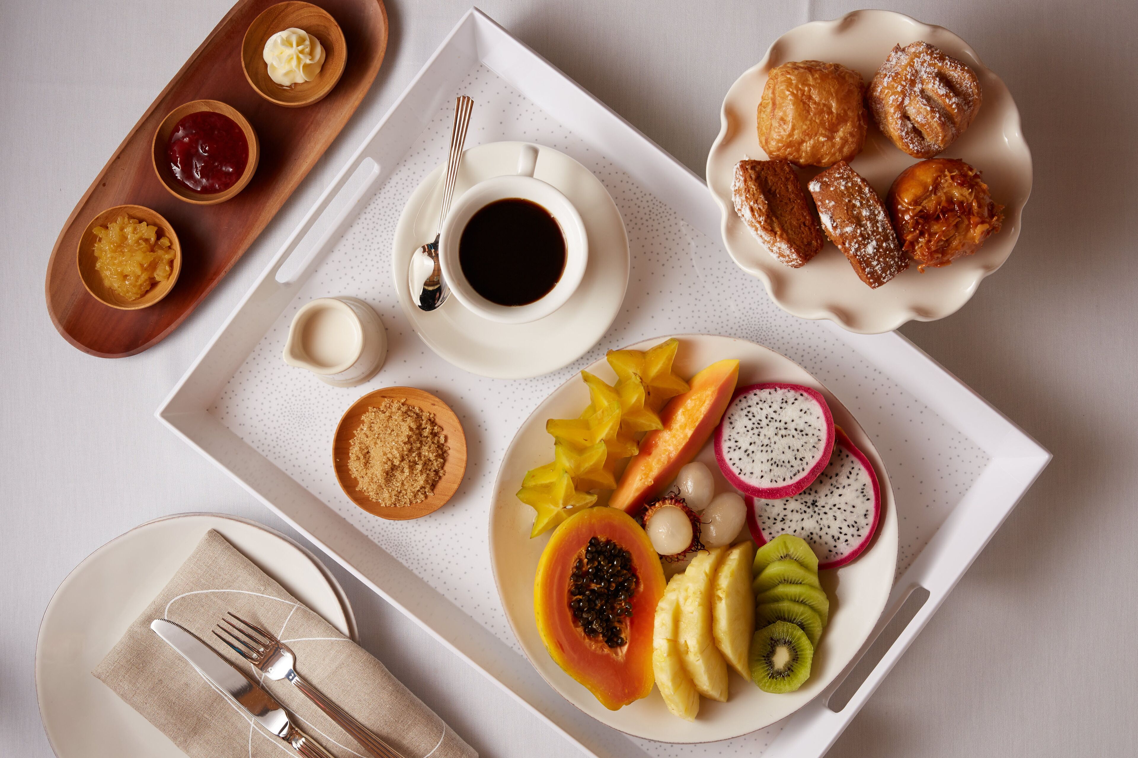 Bandeja de desayuno con pasteles, frutas y salsas.