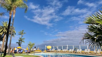 Una piscina al aire libre, sombrillas, sillones reclinables de piscina