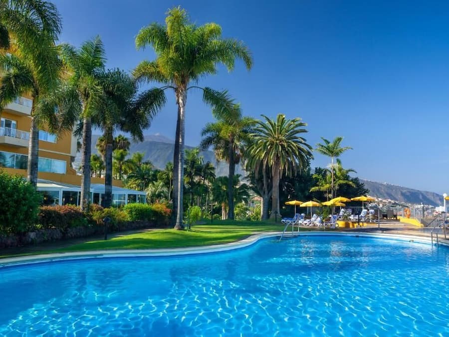 A swimming pool with palm trees and a building in the background.