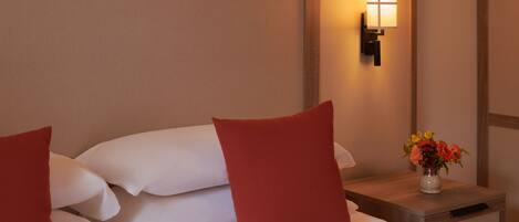 Una habitación de hotel con una cama bien hecha, una mesita de noche con un florero y una lámpara de pared.