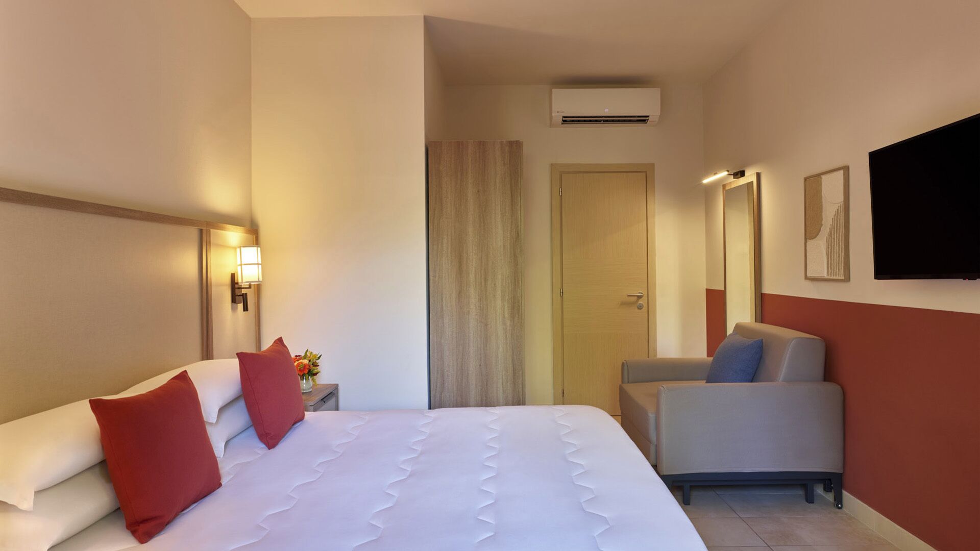Une chambre d’hôtel équipée d’un lit, d’un bureau, d’une chaise, d’une télévision et d’un appareil de climatisation.