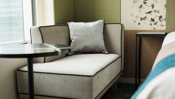 Ein modernes Hotelzimmer mit einer Couch, einem kleinen Tisch und einer Wand mit Blattmuster.