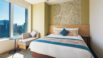 A hotel room with a large bed, a seating area, a city view, and a map on the wall.