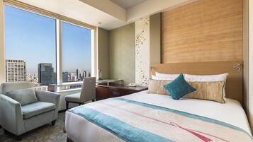 A hotel room with a large bed, a desk, a chair, and a view of the cityscape.