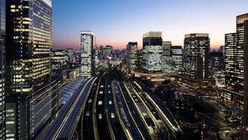 Un paisaje urbano al atardecer con rascacielos iluminados y una autopista de varios niveles.