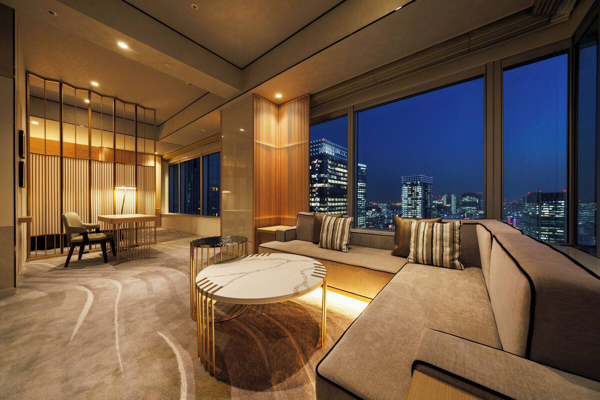 A modern living room with a city view, a sofa, a coffee table, and a dining area.