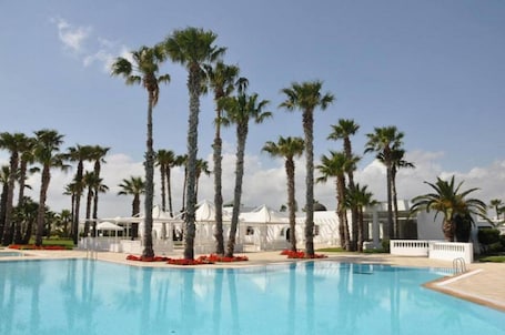 Una piscina al aire libre, sombrillas, sillones reclinables de piscina