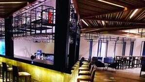 A bar area with stools and a counter, a seating area with tables and chairs, and a patterned floor.