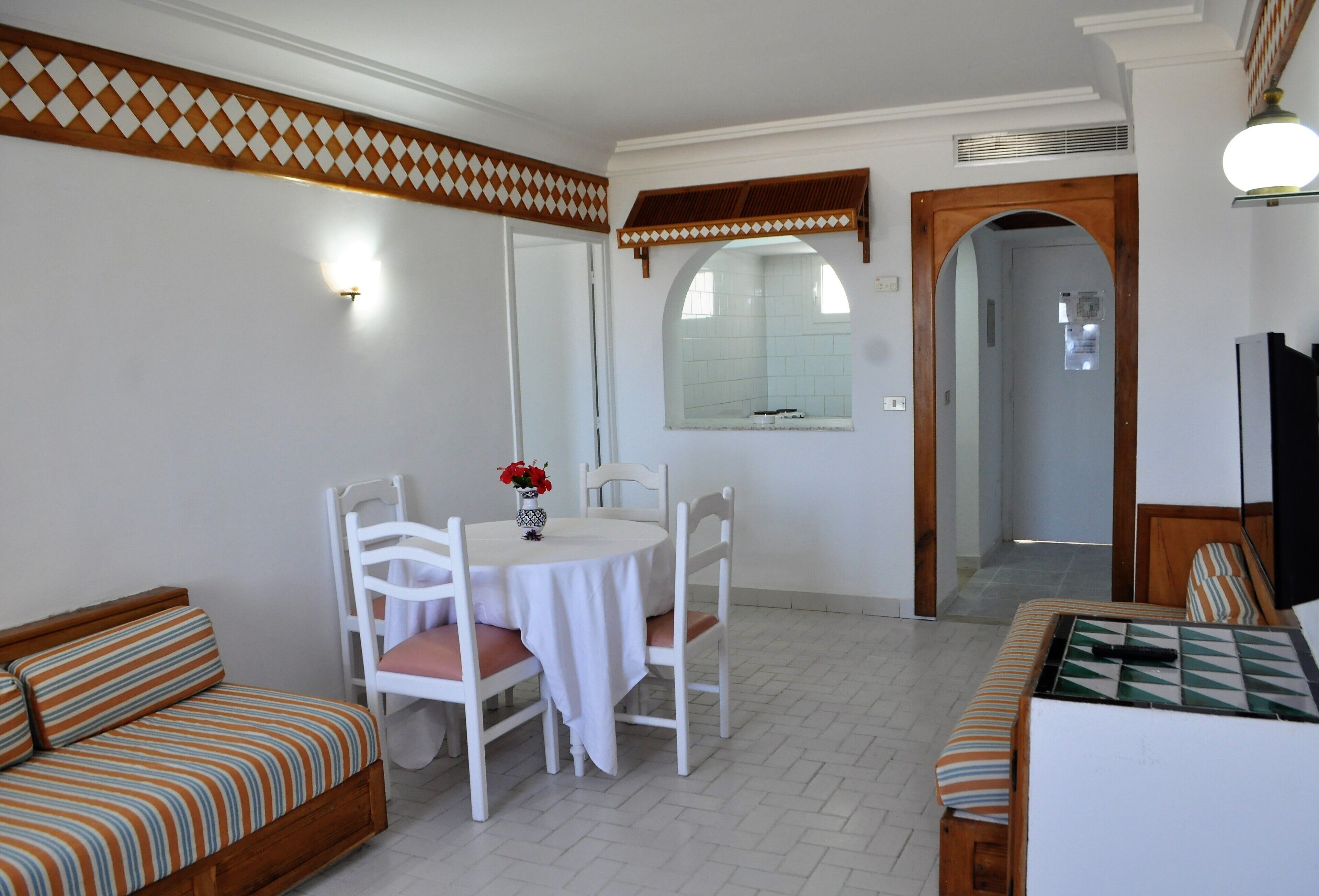 Una habitación con una mesa de comedor, sillas, un sofá y un televisor.