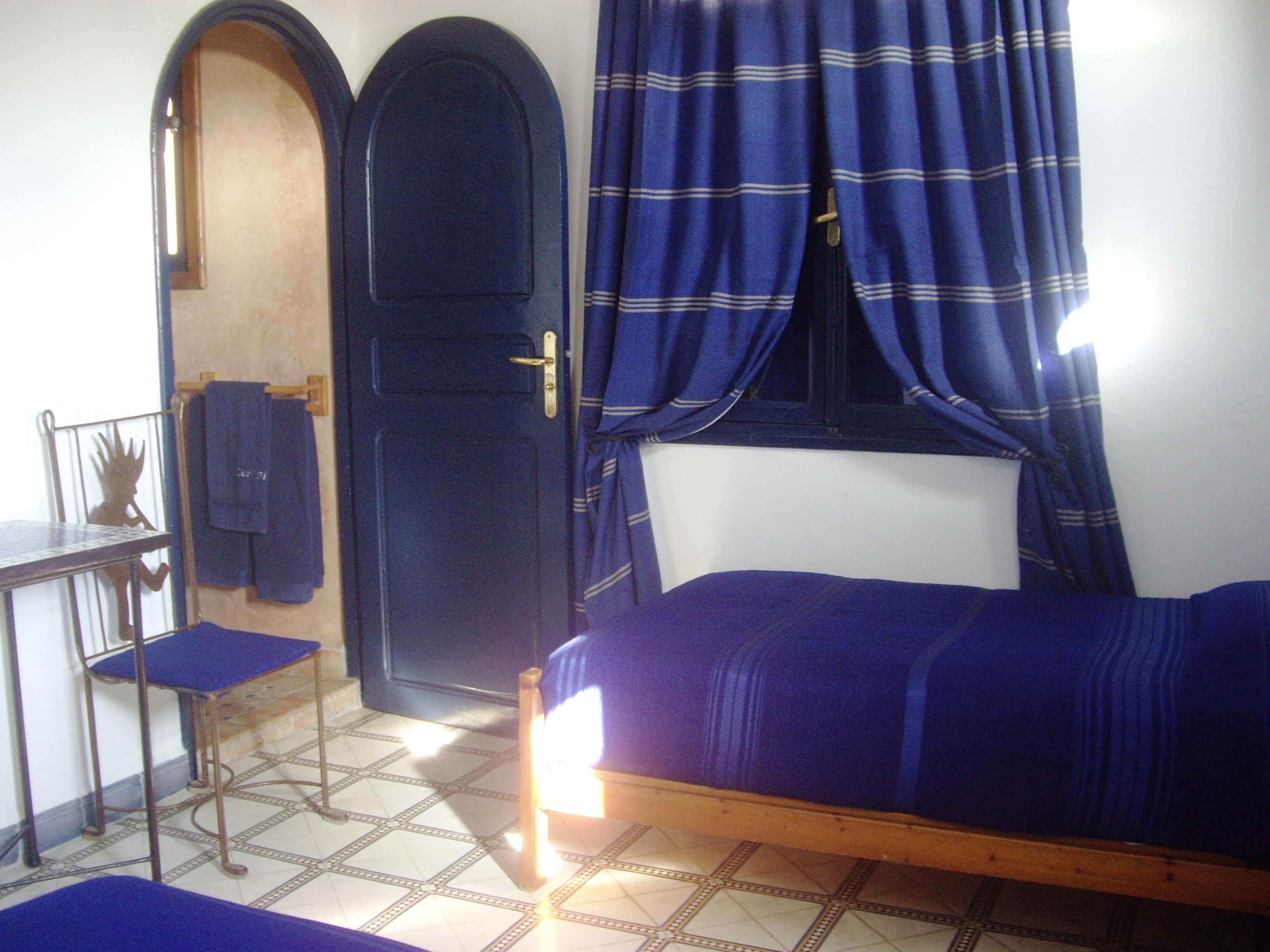 A bedroom with a bed, a desk, and a chair.