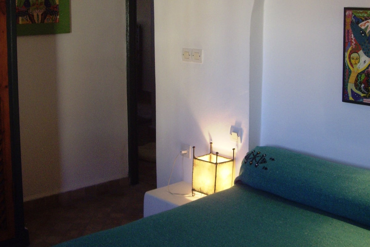 Un dormitorio con una cama, una lámpara de pared y un cuadro.