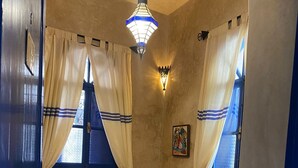 A room with a bed, curtains, a wall-mounted light, and a small painting.