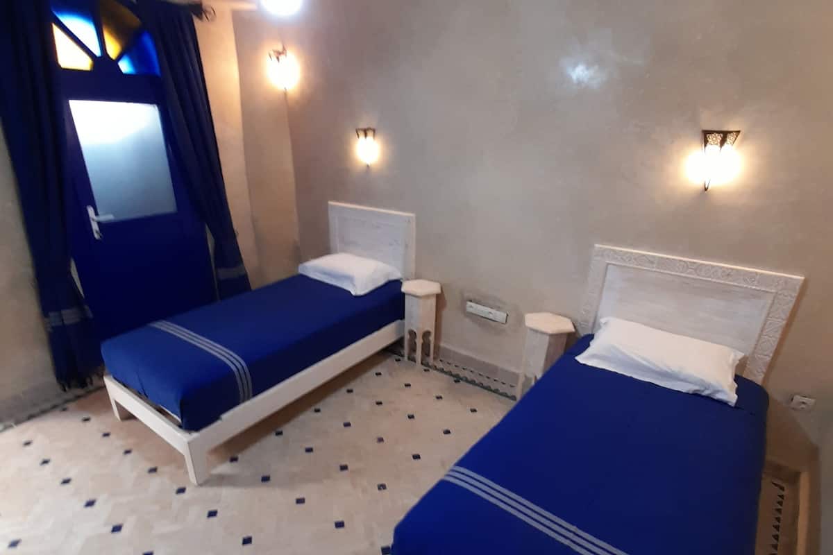Un dormitorio con dos camas, una ventana con cortinas e iluminación empotrada.