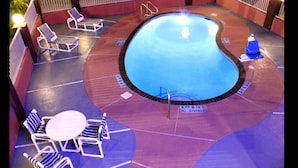 A swimming pool with lounge chairs and a table, surrounded by a deck with a '3 FT 6 IN NO DIVING' sign.