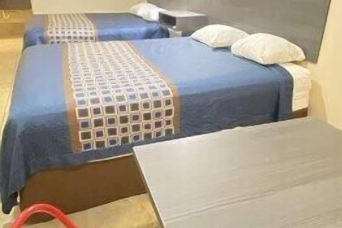 A hotel room with two beds, a desk, and a red chair.