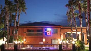 Un hotel con un letrero que dice "Texas Inn" y un área de piscina al frente.