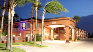 A hotel with a prominent sign, a covered entrance, and a parking lot.