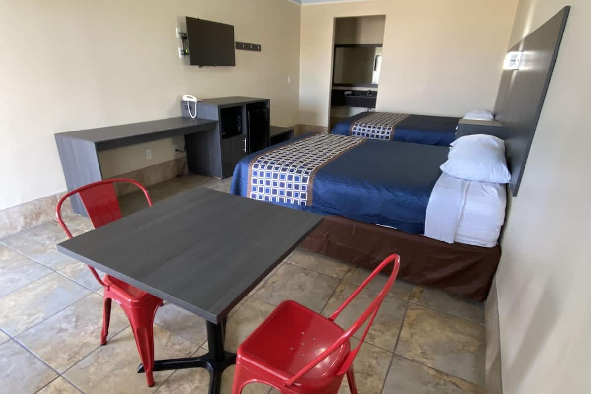 A compact hotel room with a bed, a desk, a chair, and a small table.
