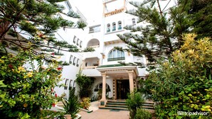 Un edificio blanco con varios balcones y una entrada central.