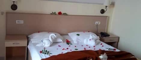 A hotel room with a bed, a nightstand, a wall-mounted lamp, and a framed picture above the bed.