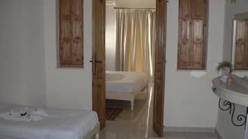 A bedroom with a bed, a bathroom with a mirror, and a door leading to another room.
