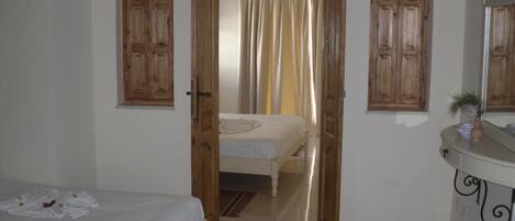 Un dormitorio con cama, un baño con espejo y una puerta que da a otra habitación.