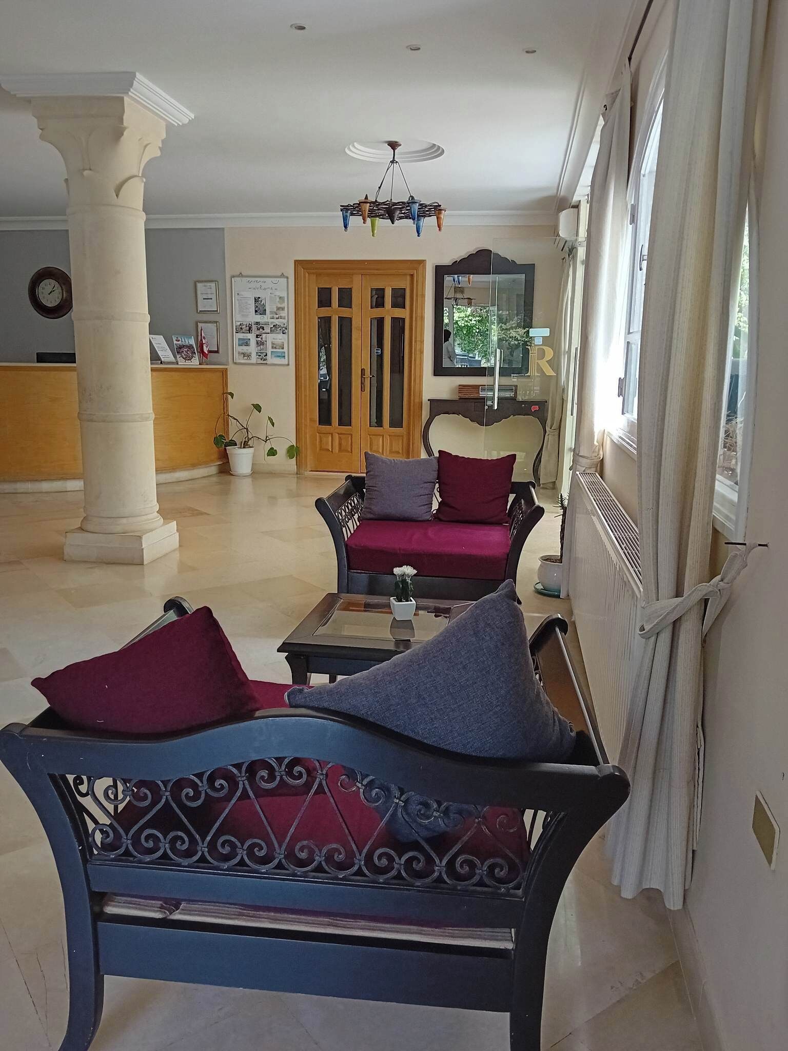 Un vestíbulo espacioso con una recepción, una puerta de madera y un área de estar con dos sofás y una mesa de centro.