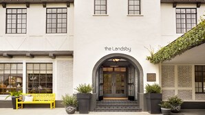 A building with a white facade, a red-tiled roof, and a sign reading "the Landsby." - The Landsby (Solvang)
