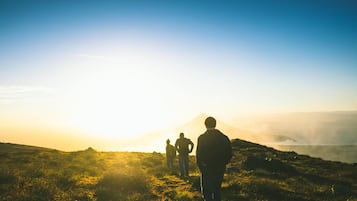 A group of people hiking on a grassy hill with a mountain in the background.