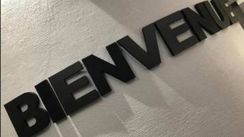 Un letrero negro con la palabra 'BIENVENUE' sobre una pared con textura.