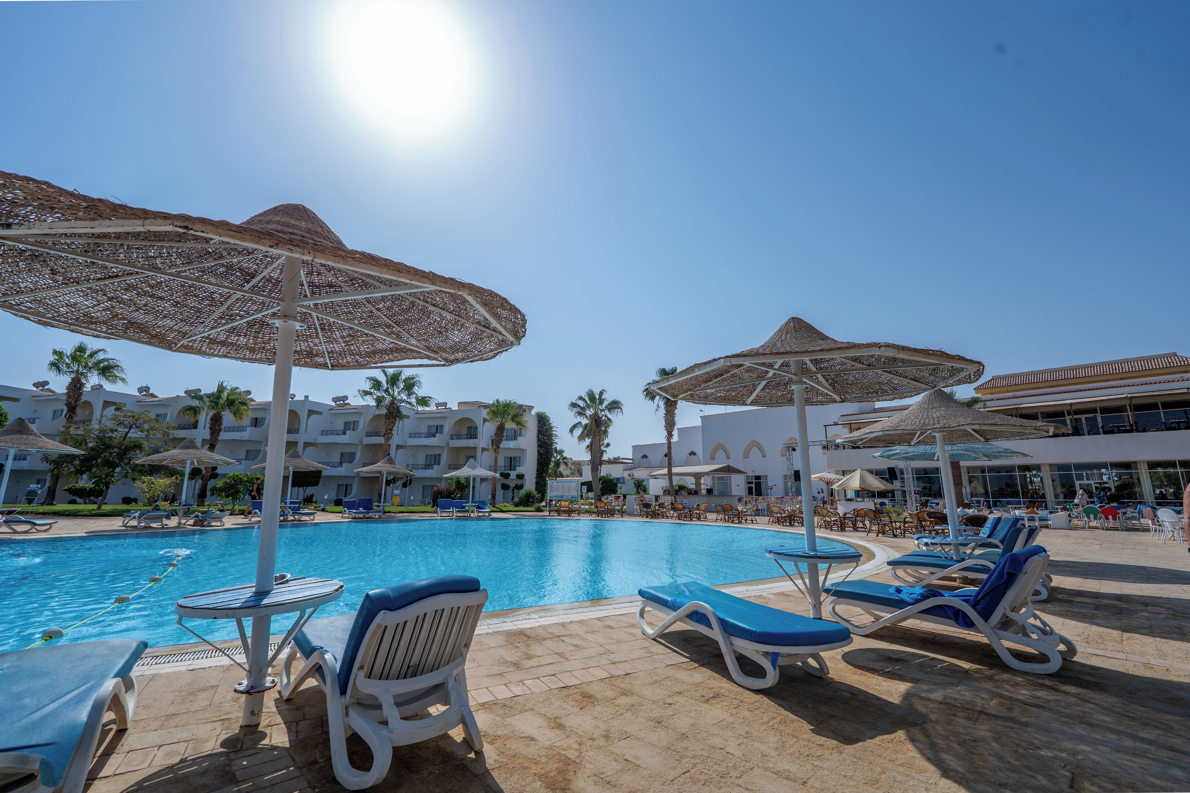 A poolside area with lounge chairs, umbrellas, and a clear blue sky.