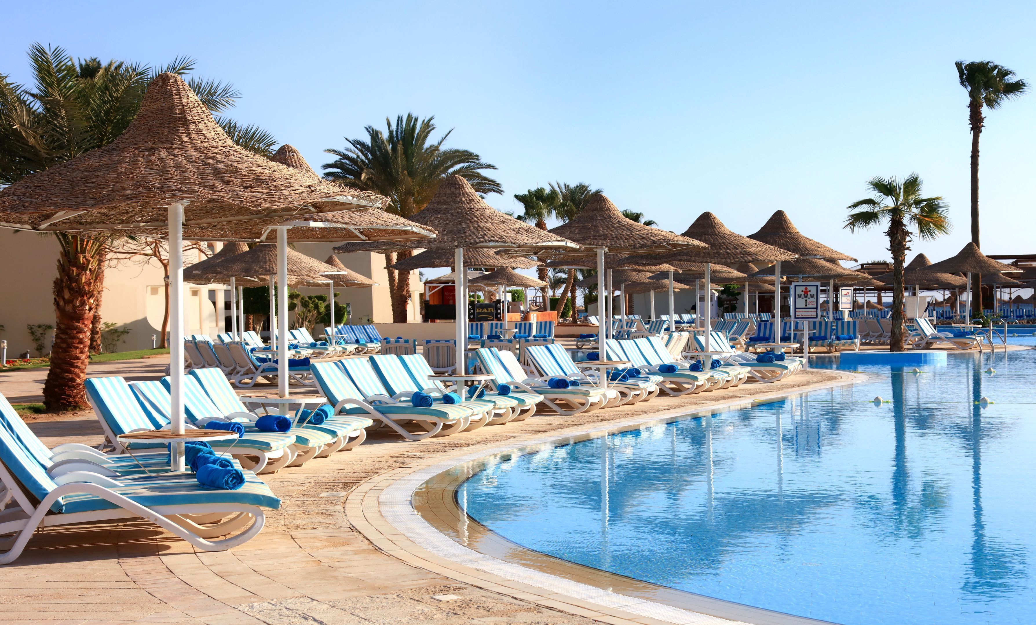 A poolside area with lounge chairs, umbrellas, and a bar.