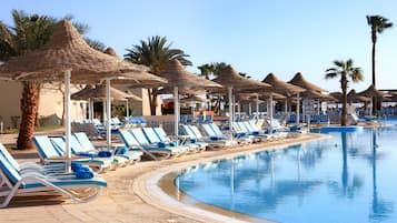 A poolside area with lounge chairs, umbrellas, and a bar.