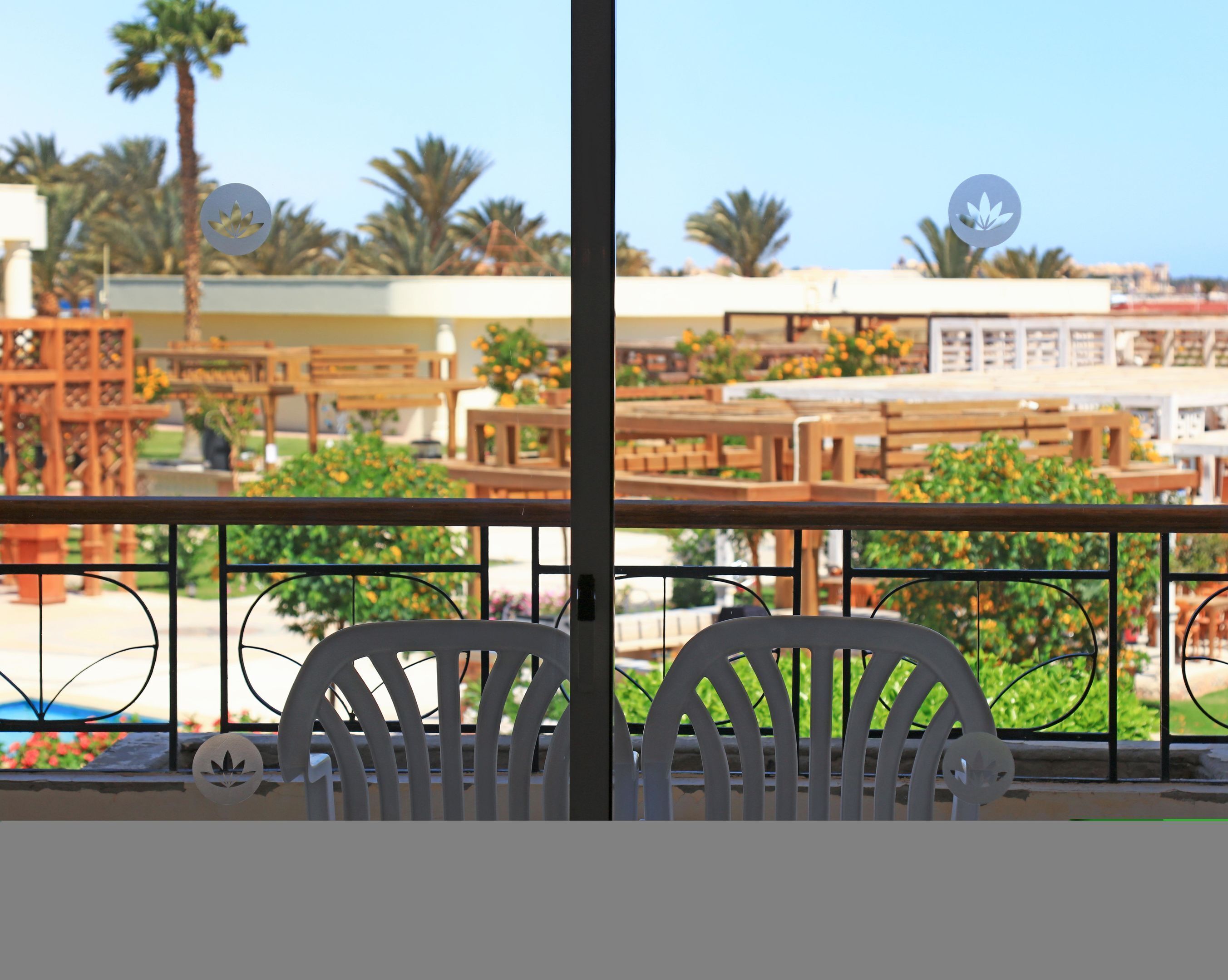 A balcony with a view of outdoor seating and palm trees.