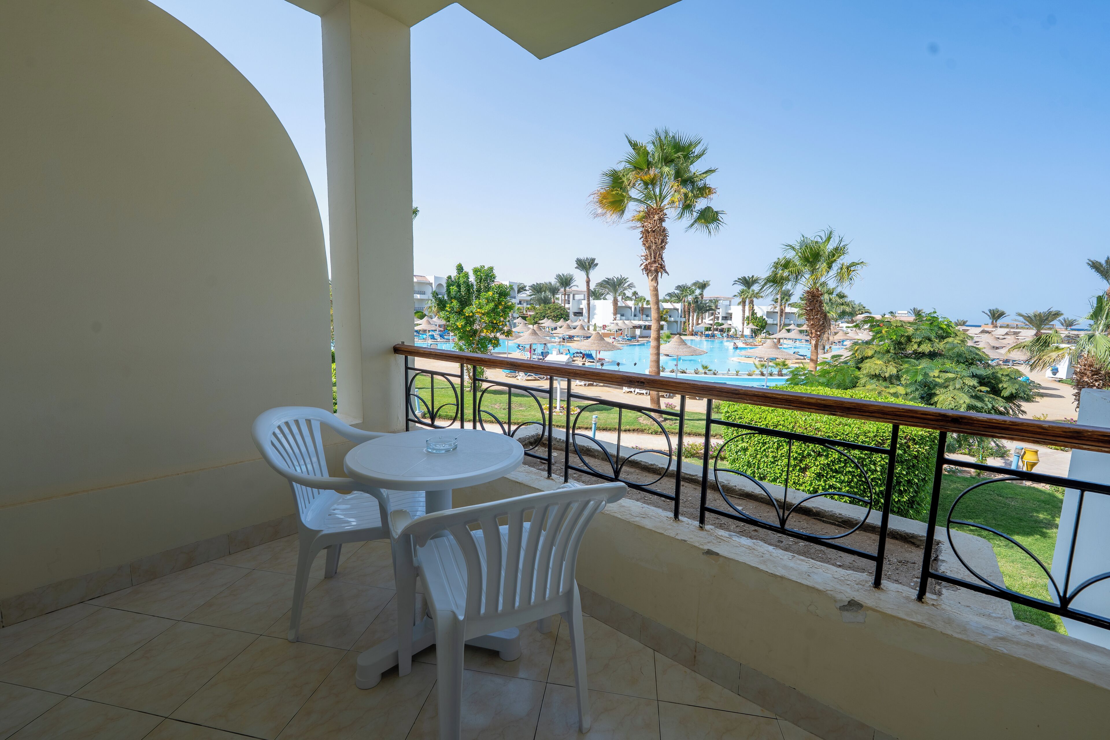 A balcony with a view of a swimming pool and palm trees.