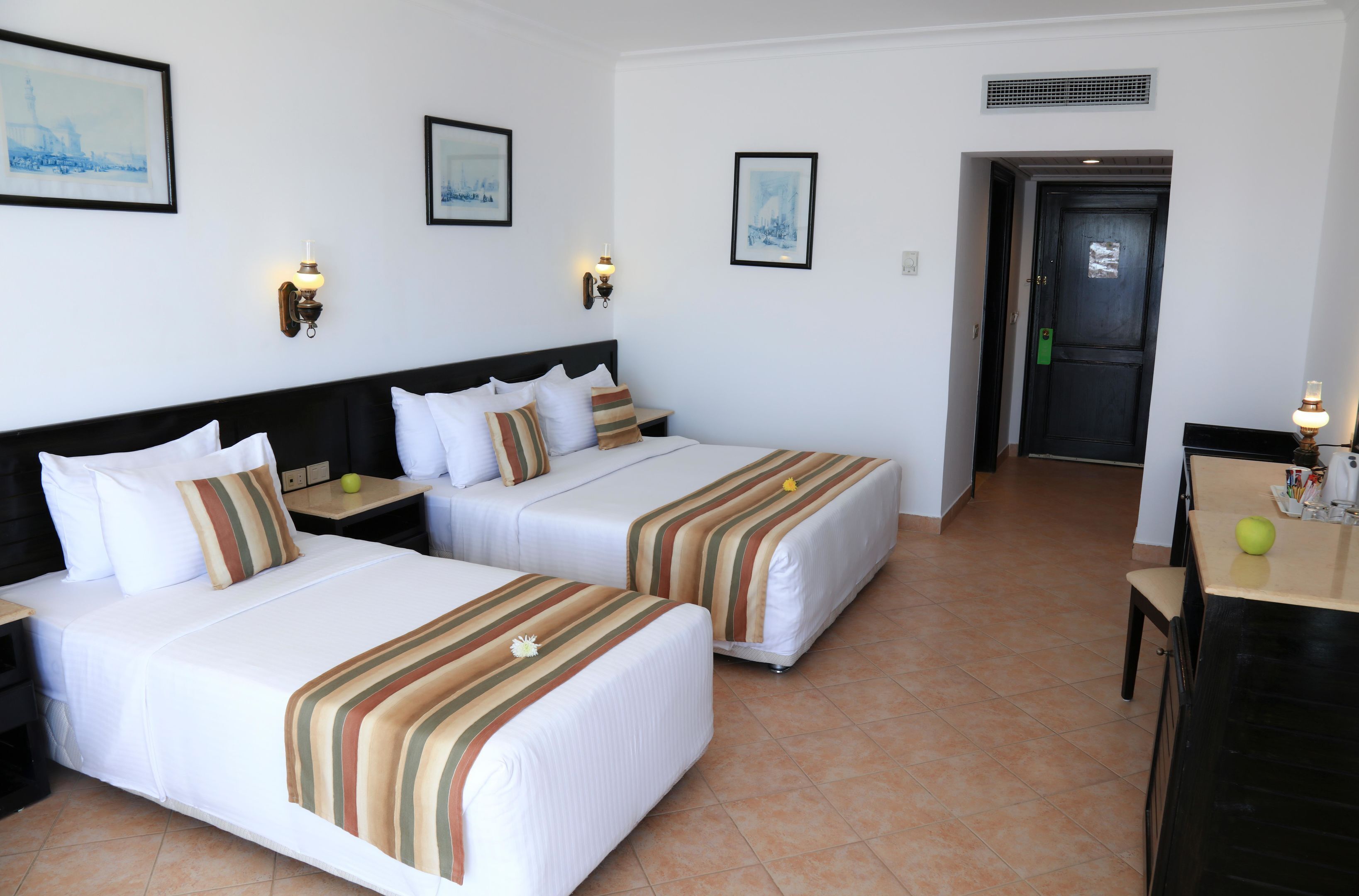 Een hotelkamer met twee bedden, een bureau en een deur.