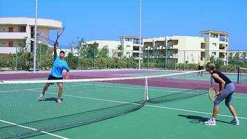 A tennis court with a net in the middle, surrounded by a fence.