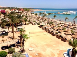 A beach resort with numerous thatched umbrellas, palm trees, and a clear view of the sea. - Giftun Azur Resort - All inclusive (Hurghada)