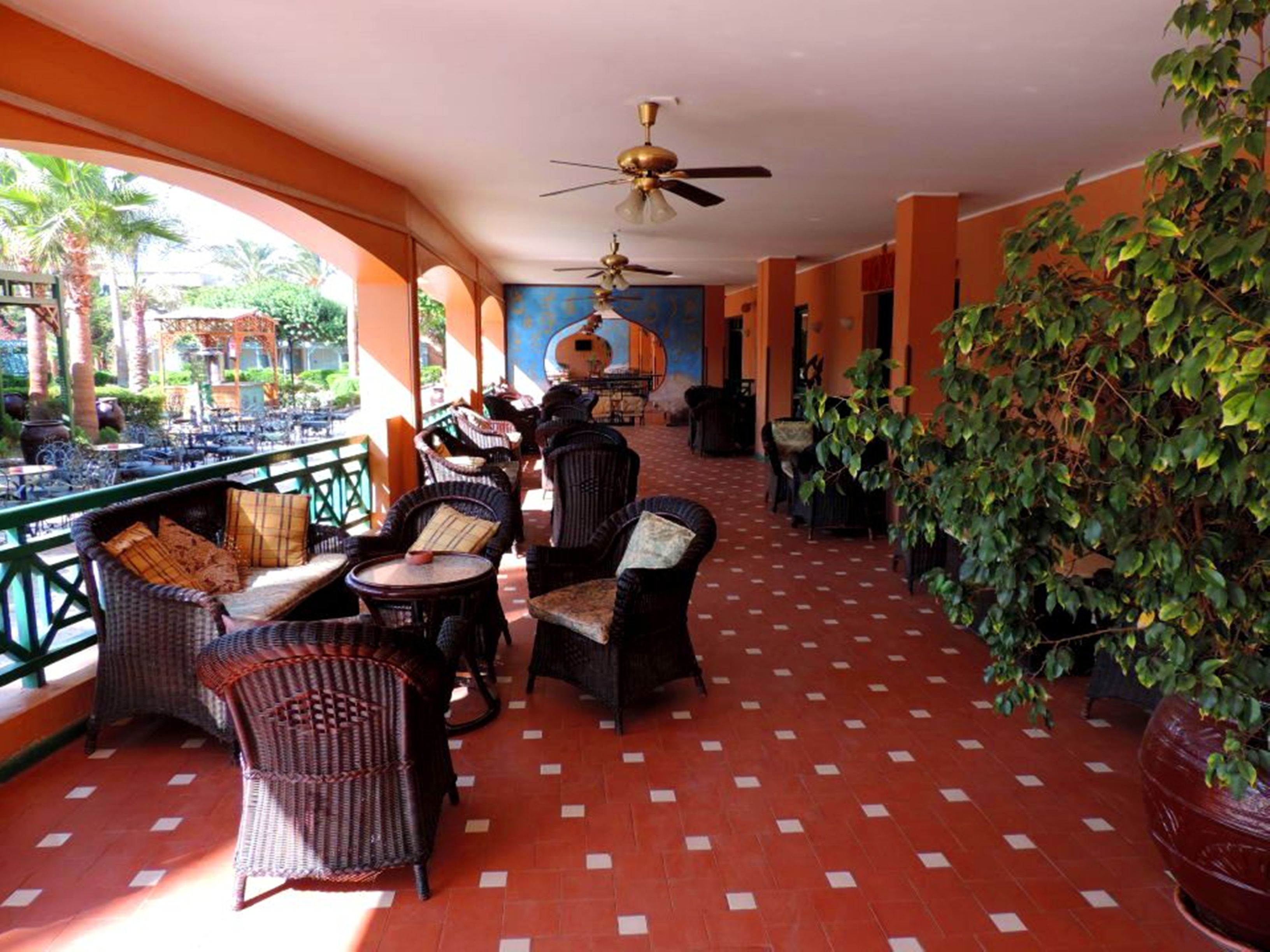 An outdoor seating area with wicker furniture, a ceiling fan, and a view of the garden.