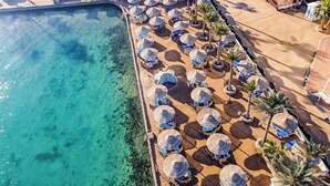 An aerial view of a beachside resort with clear turquoise water, rows of sun umbrellas, and lounge chairs. - Bel Air Azur Resort - Adults Only (Hurghada)