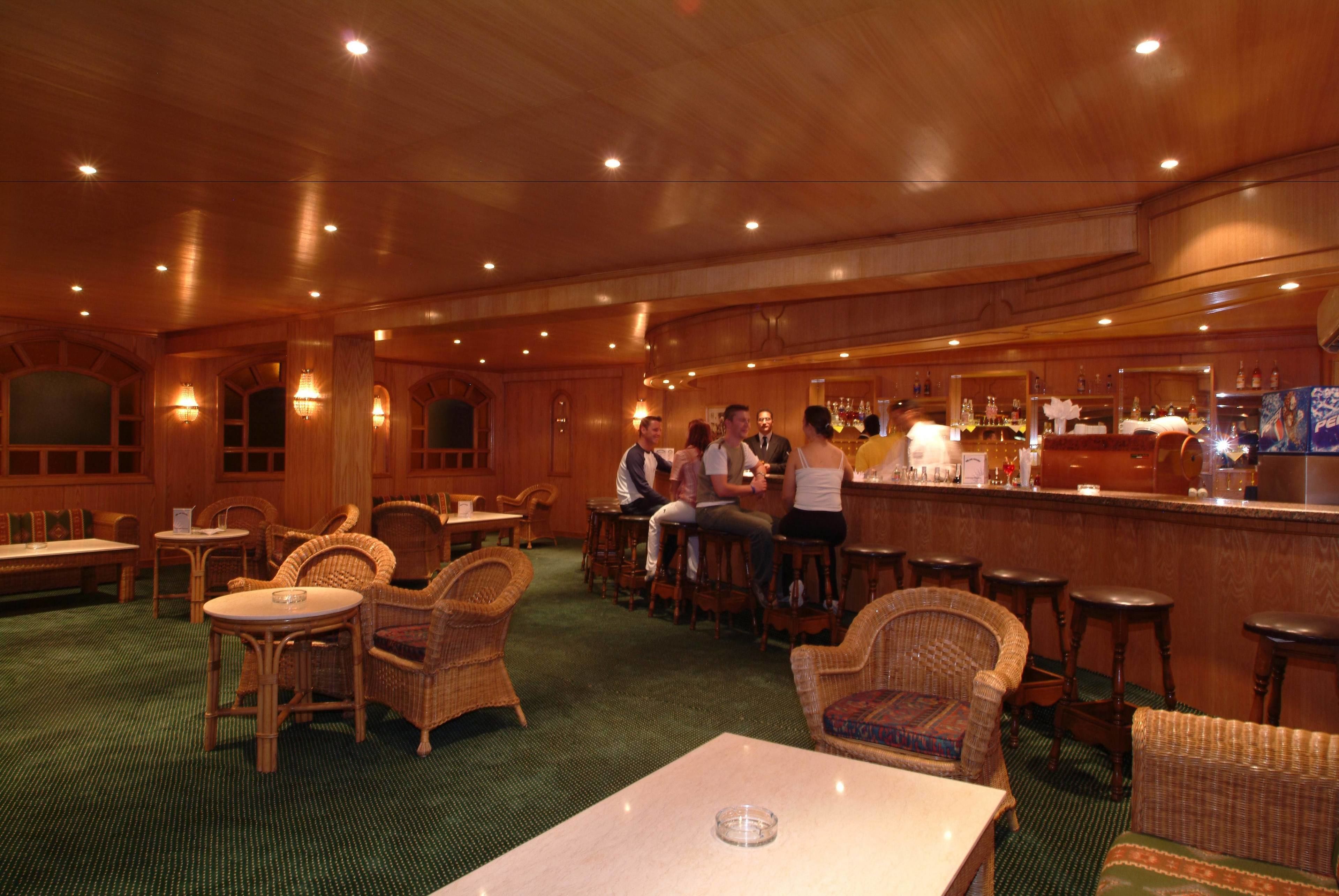 A bar area with wooden furniture and a green carpet.