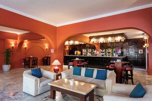 A lobby with a bar area, seating arrangements, and a potted plant.