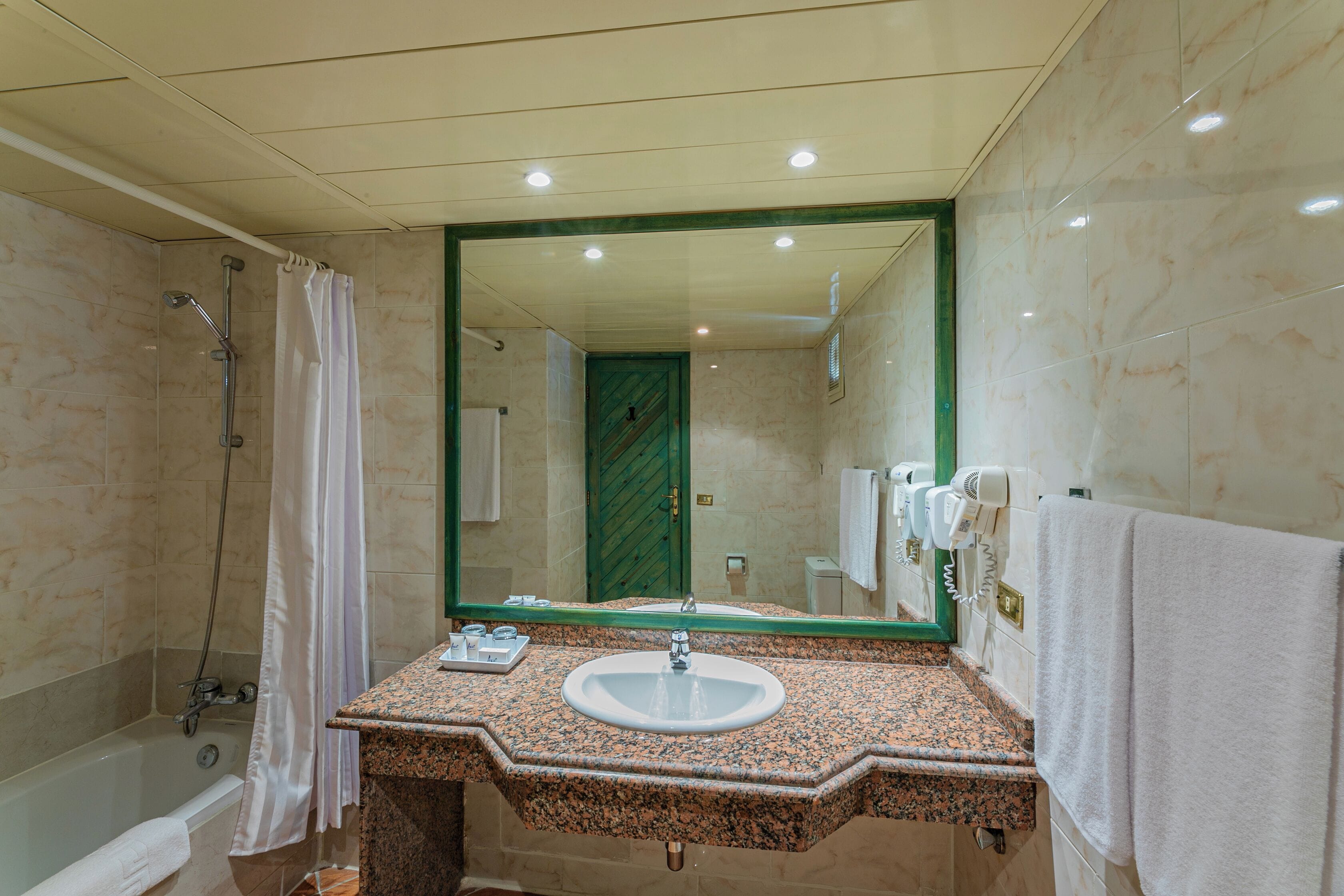 A bathroom with a sink, mirror, shower, and towel rack.