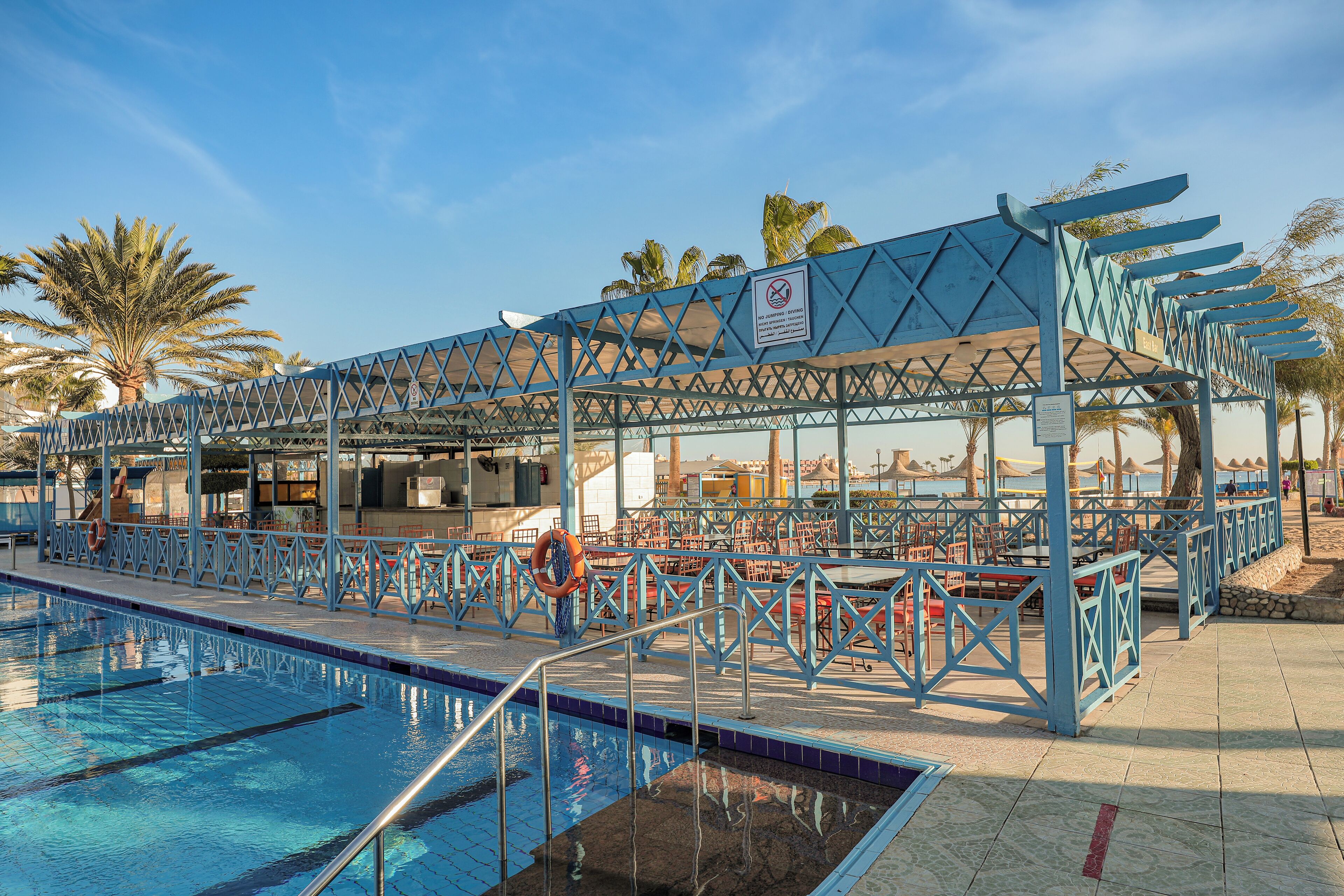 A swimming pool area with a covered seating area and lifeguard stand.