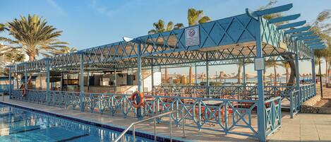 A swimming pool area with a covered seating area and lifeguard stand.