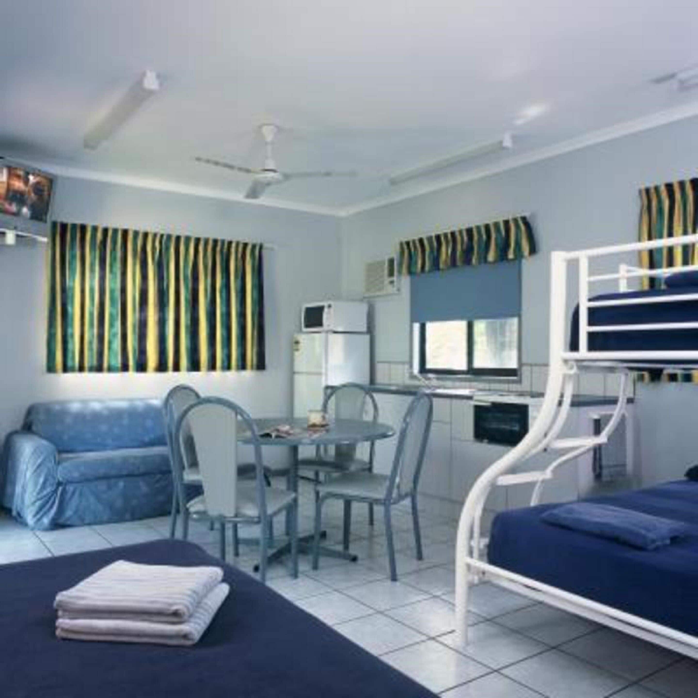 A room with a bunk bed, a desk with a chair, a small table, and a sofa.