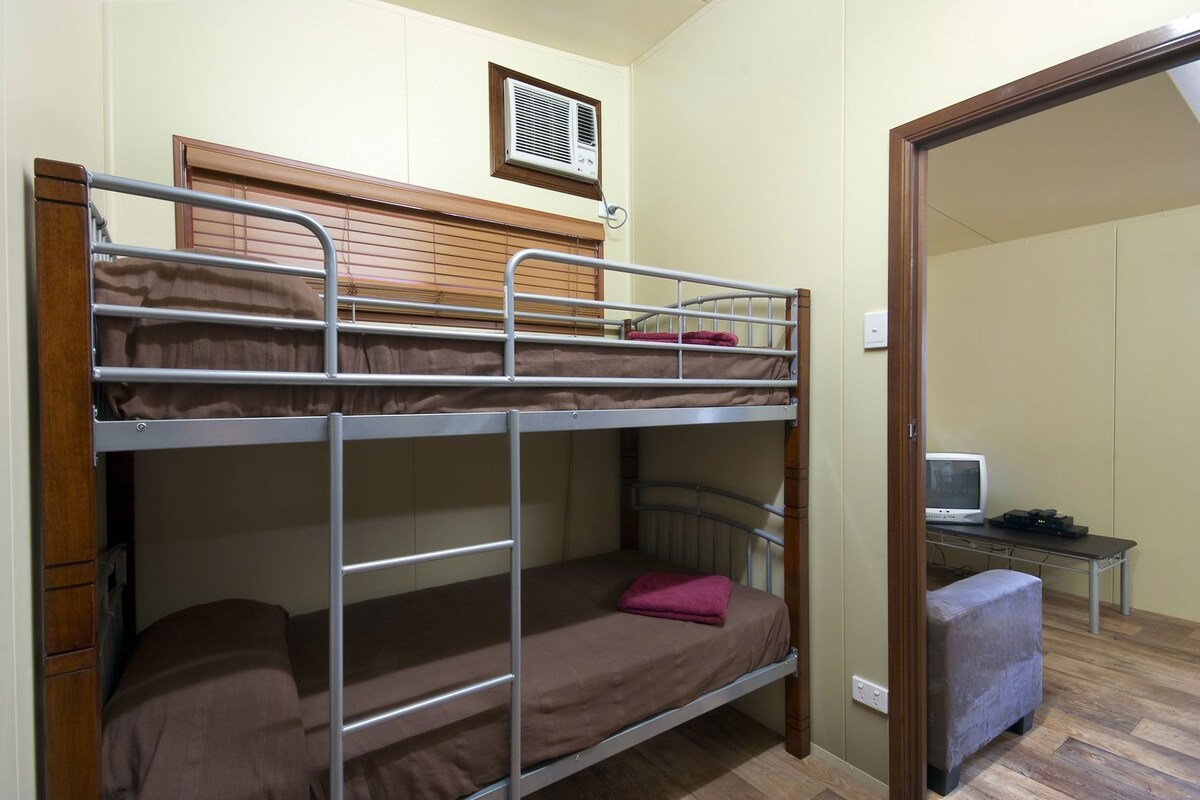 A bunk bed room with a desk and a television.